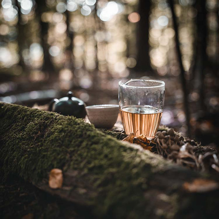 Ein ansprechendes Foto eines Tee Sets arrangiert auf einem Baumstamm