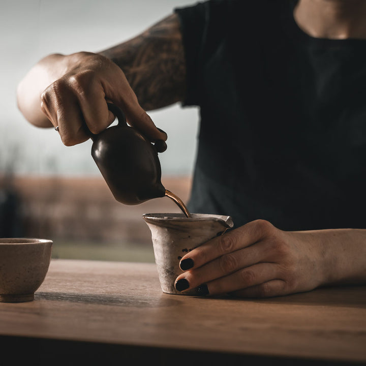 Eine Frau die einen Tee in die Tasse gießt